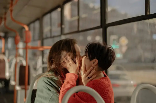 Two women kissing on a bus.